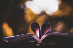 Open book with heart-shaped pages, illuminated by warm, bokeh lighting, perfect for romantic themes.